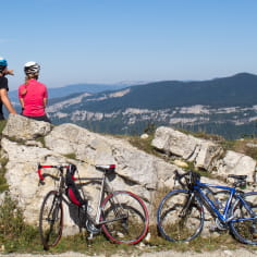 2 cyclistes arrêtés sur un rocher avec vue sur le Vercors