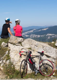 2 cyclistes arrêtés sur un rocher avec vue sur le Vercors