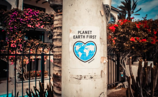 Affiche de Greenpeace 'Planet earth first' sur un poteau dans l'espace public devant un bâtiment privé
