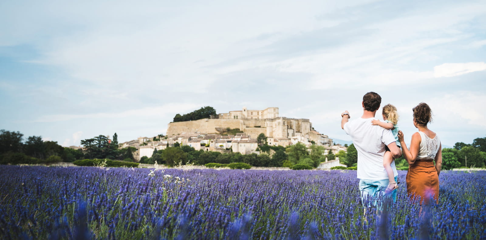 Vu sur le château de Grignan des champs de lavande avec une famille