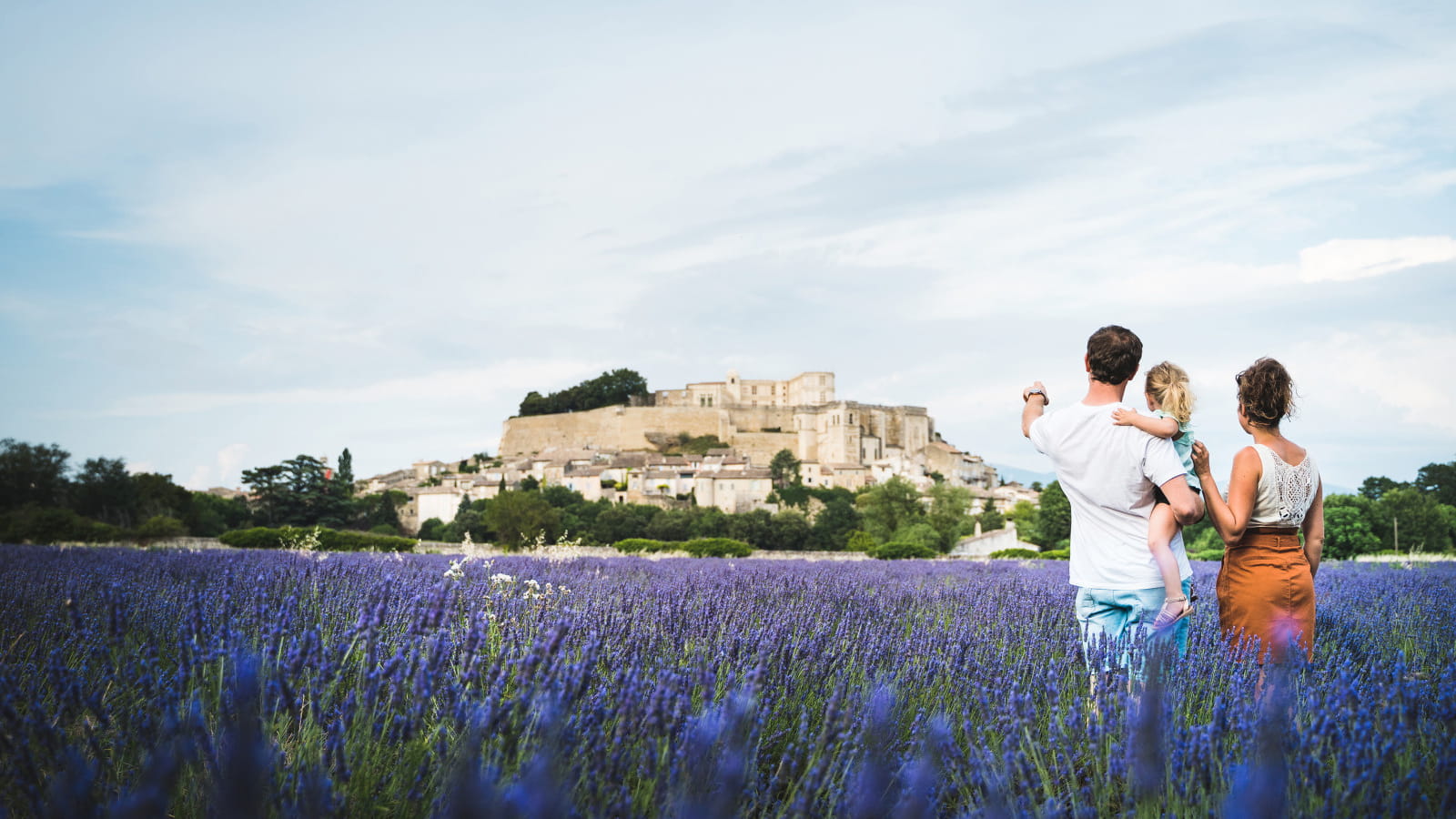 Vu sur le château de Grignan des champs de lavande avec une famille