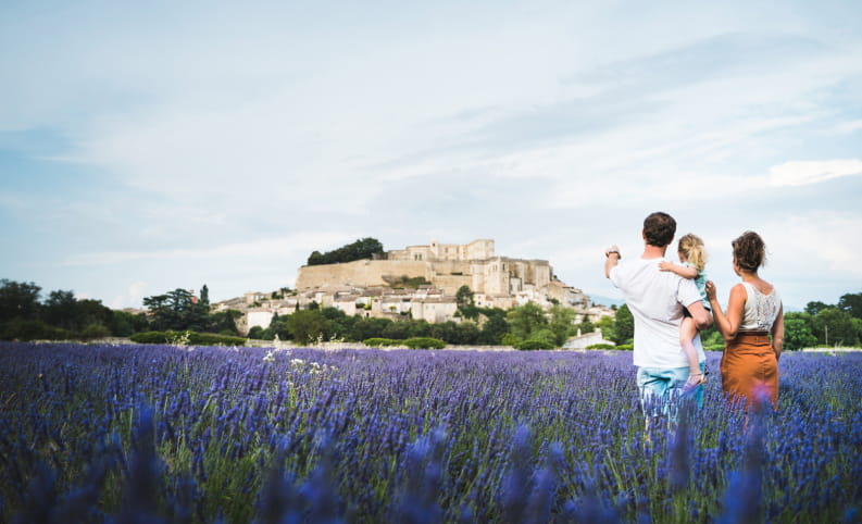 Vu sur le château de Grignan des champs de lavande avec une famille