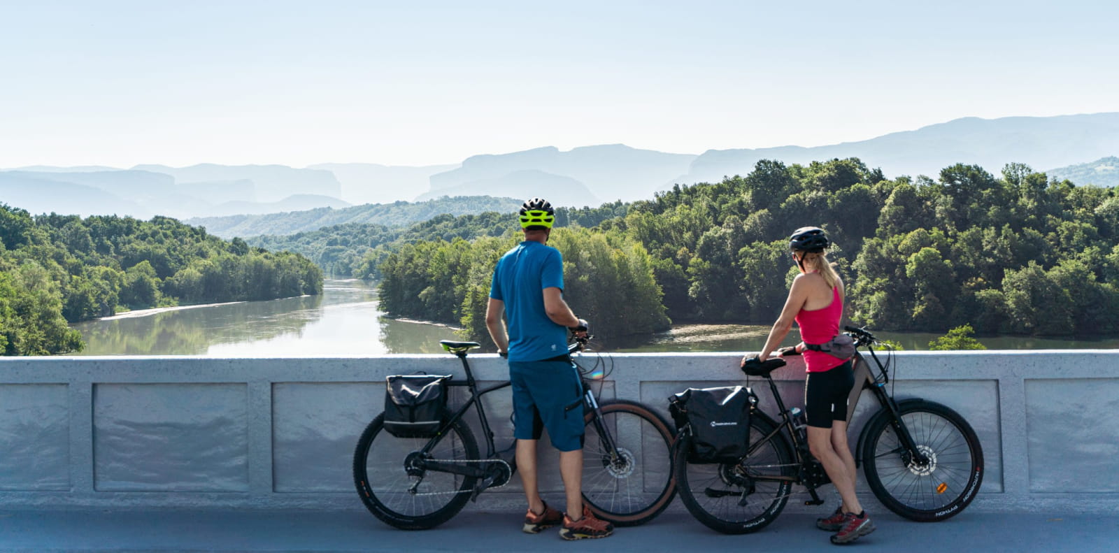 Couple de cyclistes sur la passerelle de la Belle Via au dessus du cours d'eau de l'Isère dans la Drôme